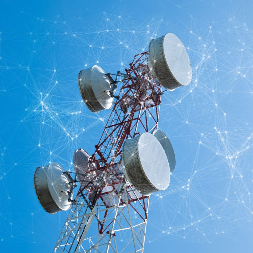 Tour de télécommunication avec antennes paraboliques sur fond de ciel bleu.