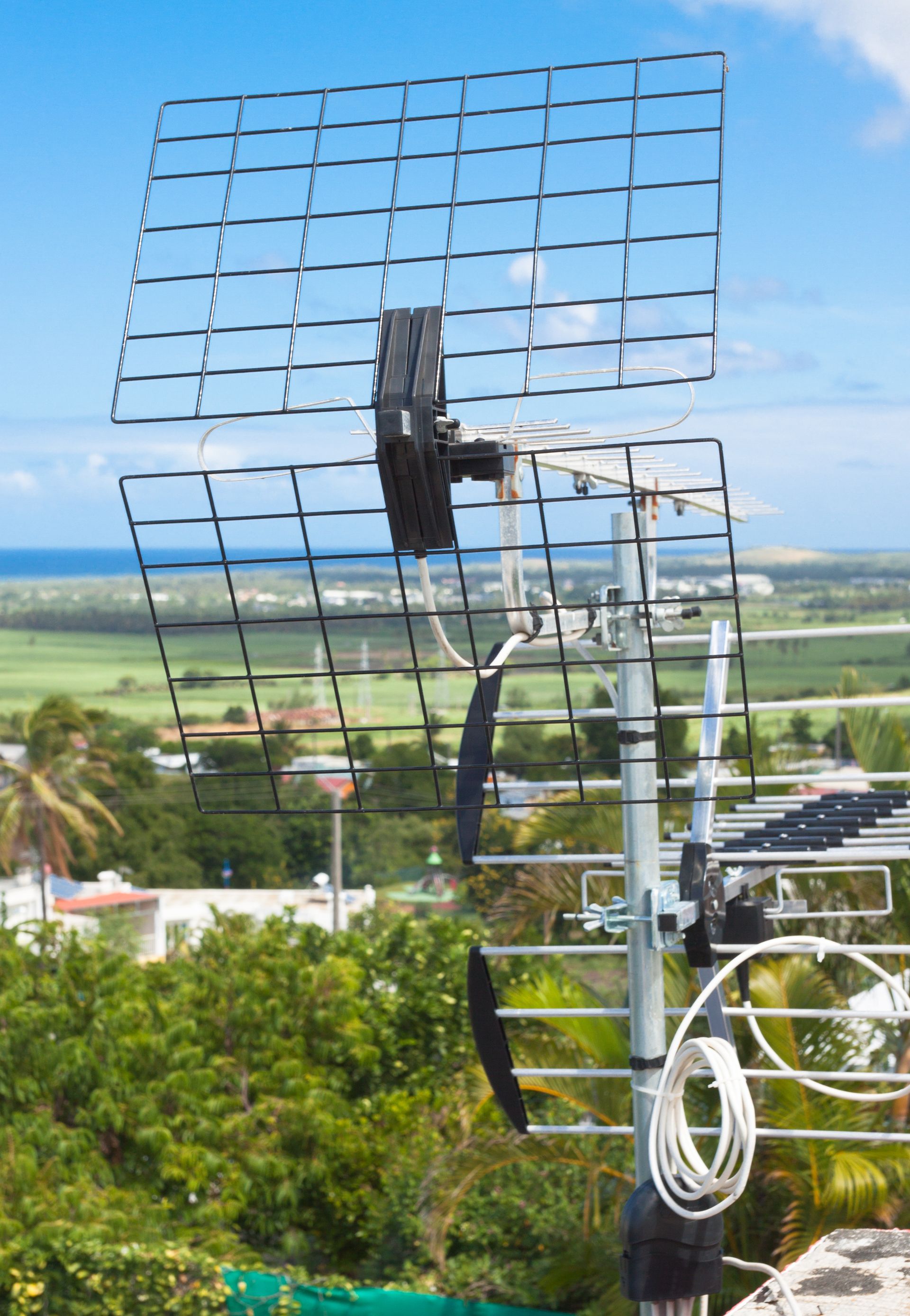 Une grande antenne de télévision extérieure se détachant sur un ciel bleu, donnant sur un paysage verdoyant.