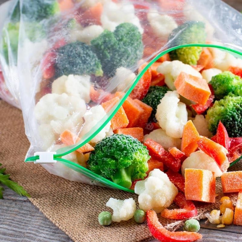 Una bolsa de plástico llena de brócoli, coliflor, zanahorias y pimientos.