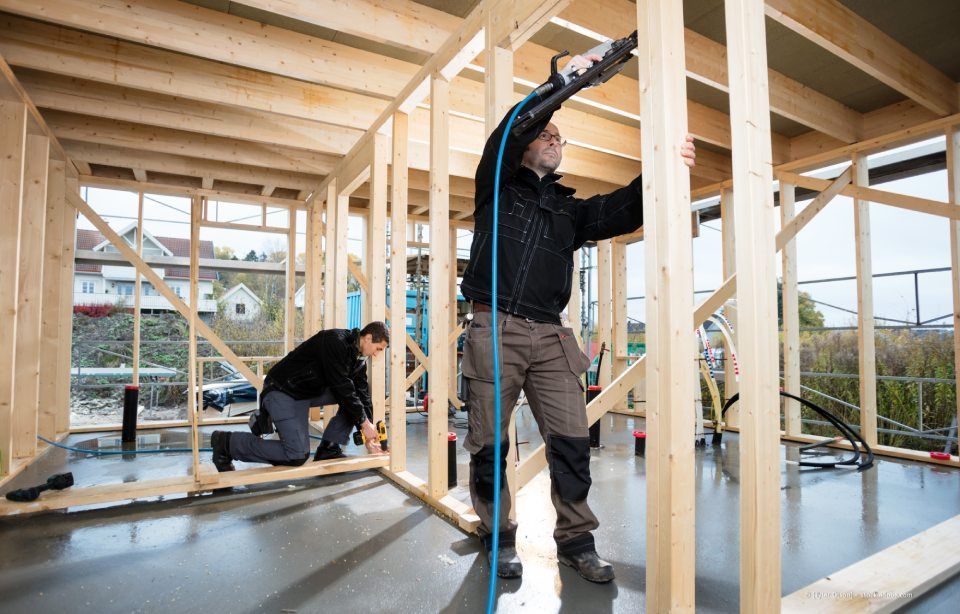 Zwei Arbeiter errichten das Holzgerüst im Inneren eines Wohnhausbauprojekts.