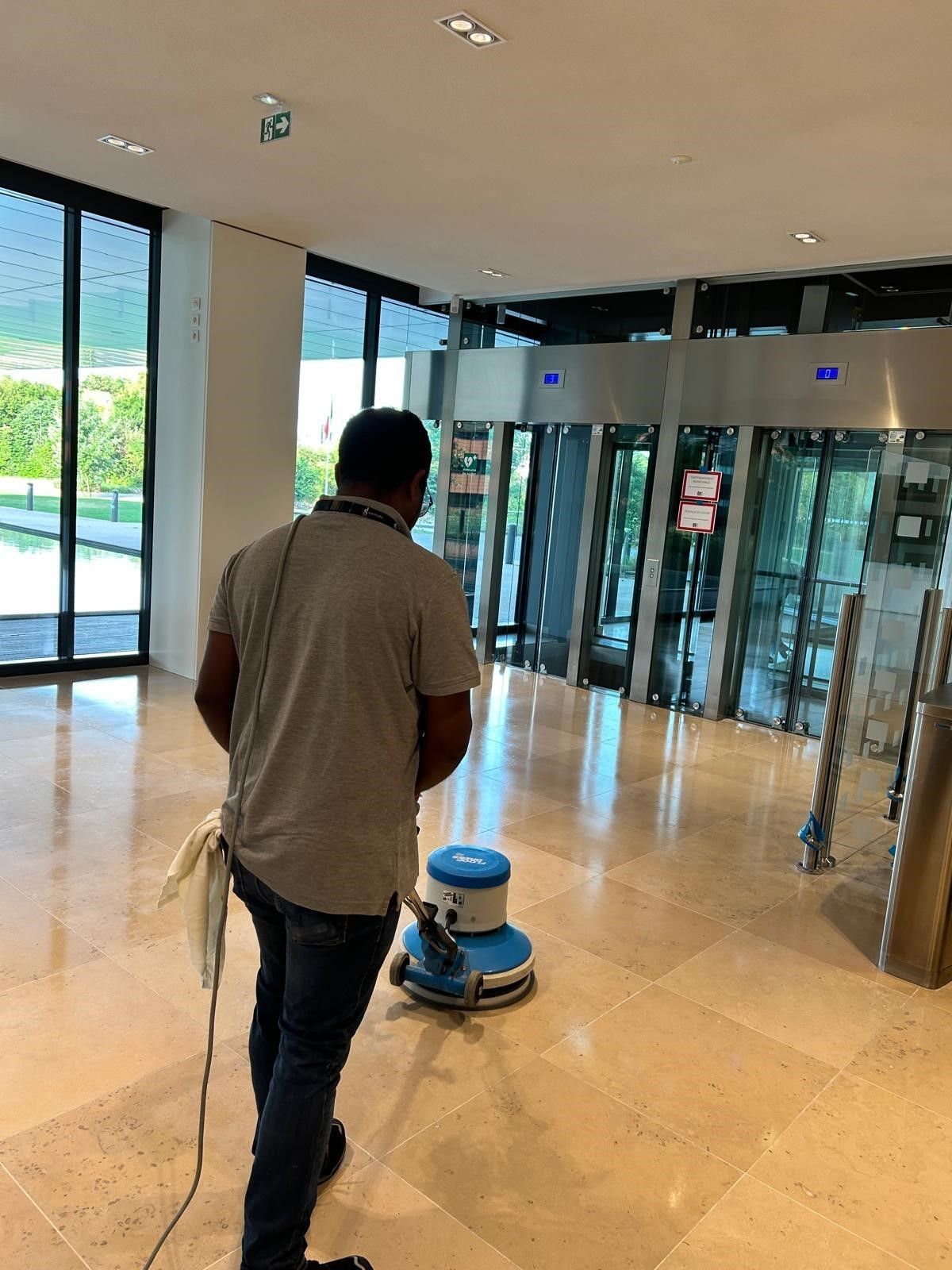 Employé de l'entreprise DB Propreté nettoyant le sol du hall d'une entreprise