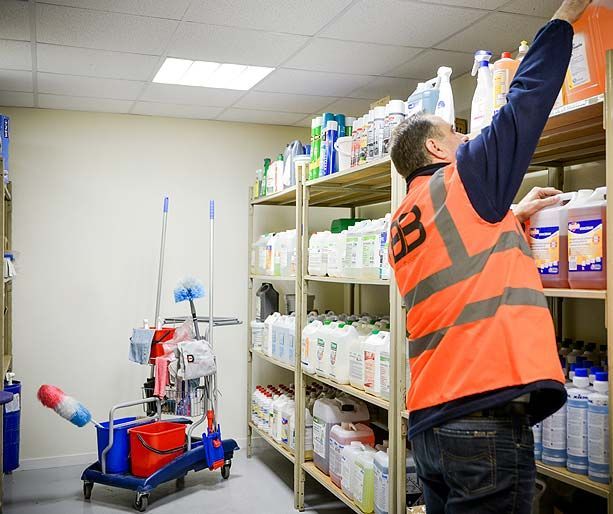 Employé portant un gilet orange en train d'attraper un produit nettoyant