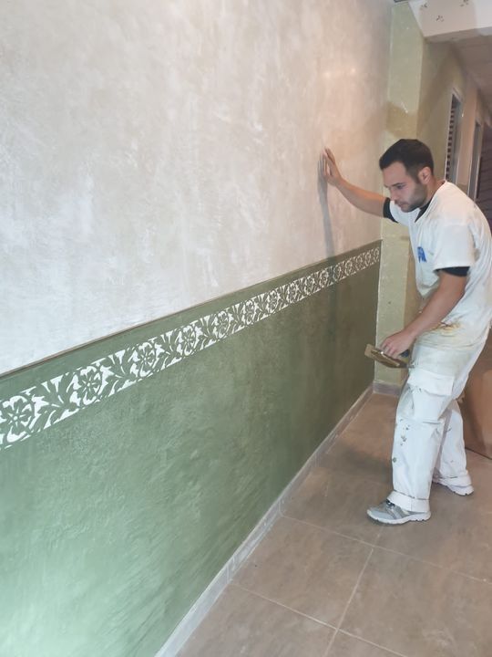 Hombre pintando ropa, aplicando pintura verde a la pared. Borde decorativo para pasillo.