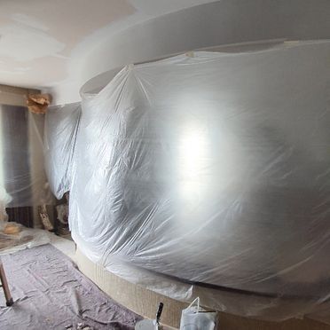 Muebles cubiertos con láminas de plástico para protección durante el pintado.