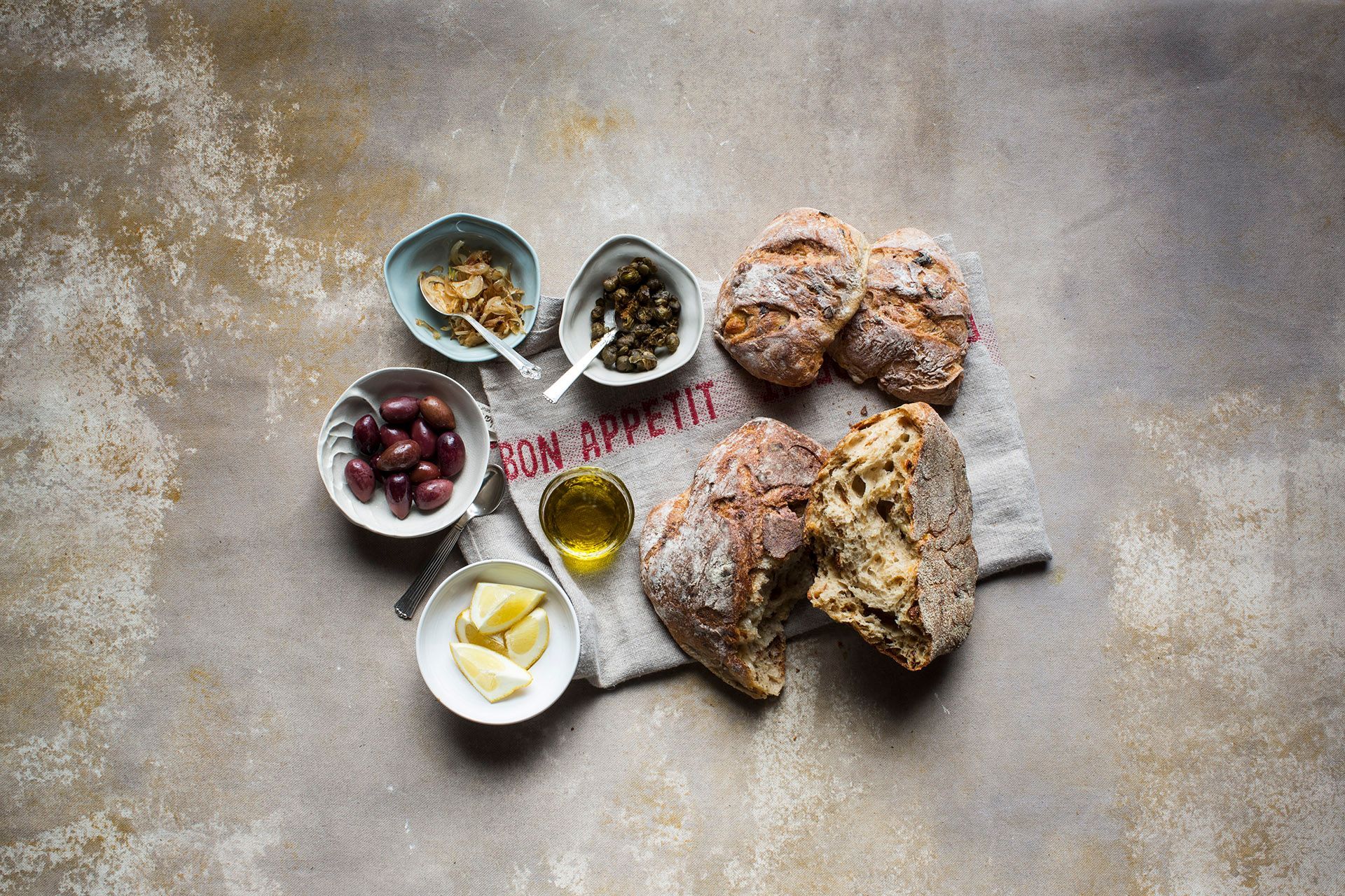 Ein Schneidebrett mit Brot, Käse, Marmelade und Obst