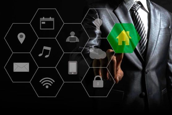 Una persona con traje señala el icono de una casa brillante. Iconos hexagonales flotan alrededor de su mano sobre un fondo oscuro.