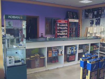 Interior de una tienda con mostrador y expositor de mercancía. Las paredes están pintadas de morado y hay vitrinas con productos.