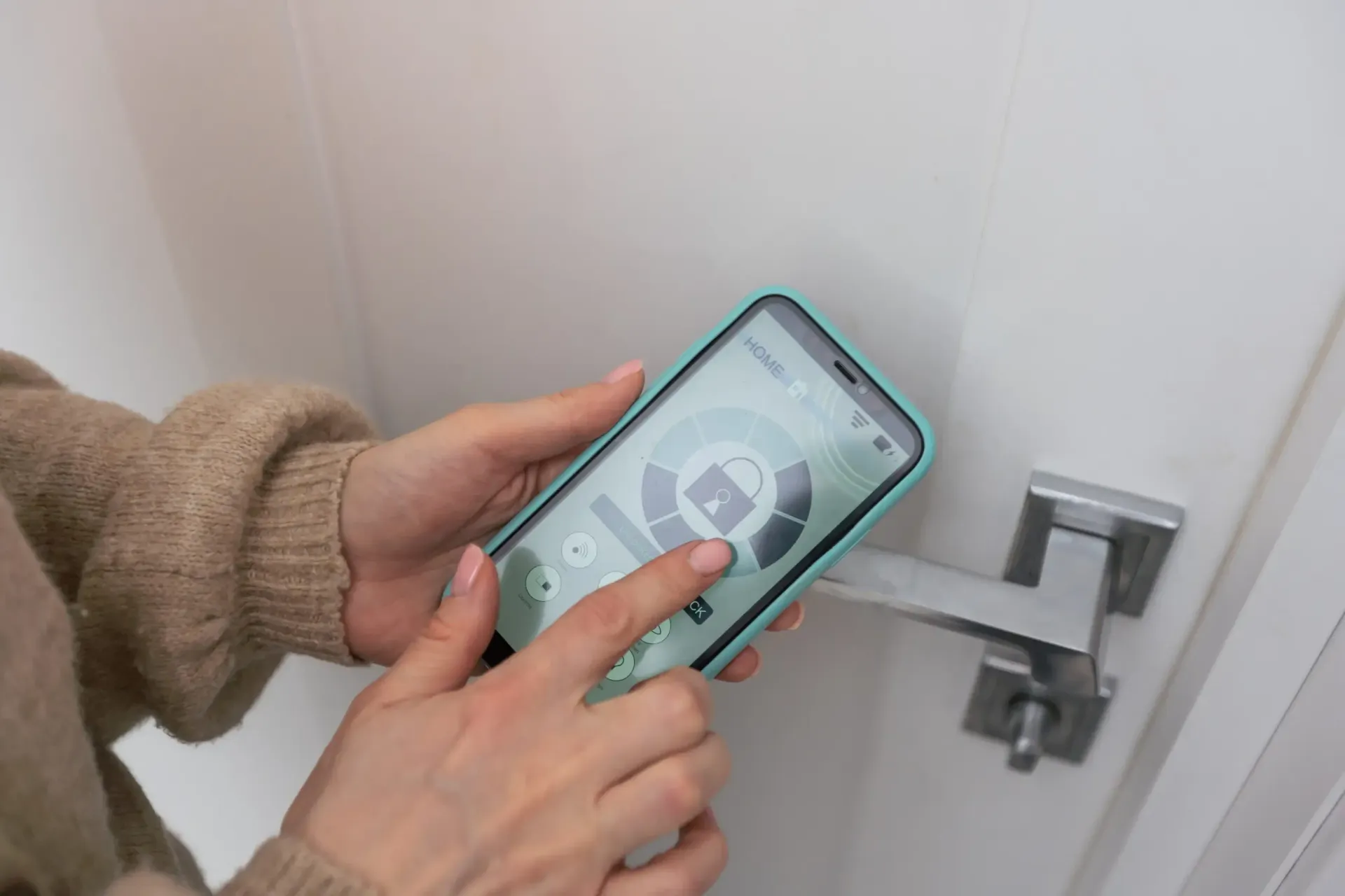 Manos utilizando un teléfono inteligente para controlar una cerradura inteligente en una puerta blanca.