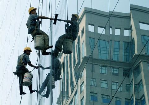 Un grupo de hombres está limpiando las ventanas de un edificio alto.