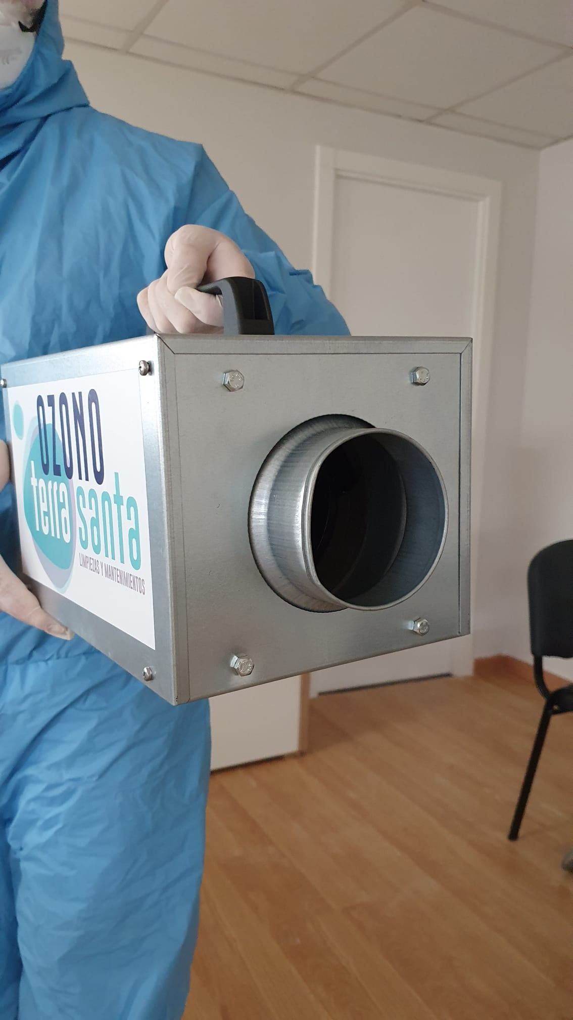 Una persona con un traje de protección sostiene una caja con un asa.