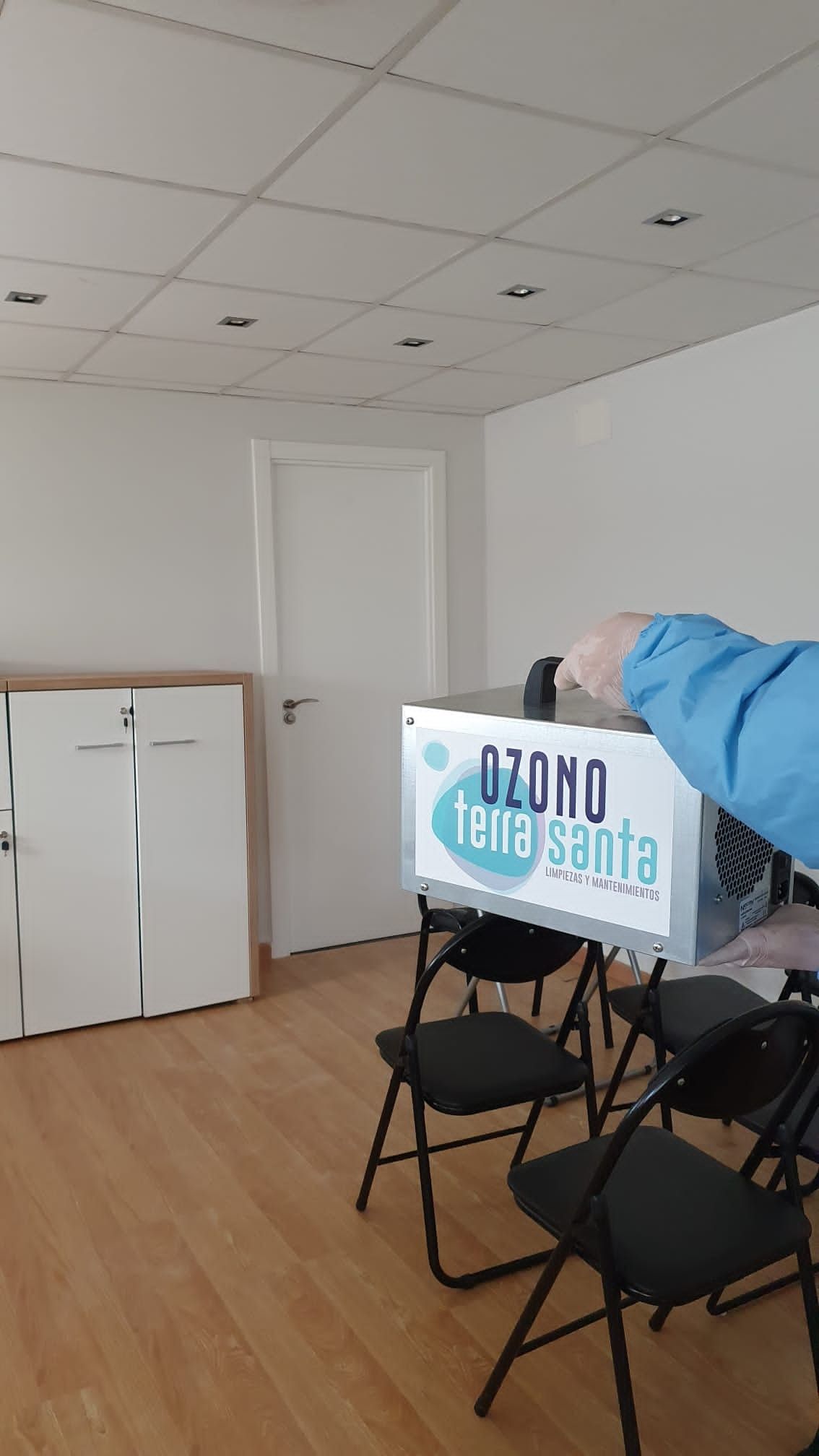 Una persona sostiene una caja en una habitación con sillas plegables.