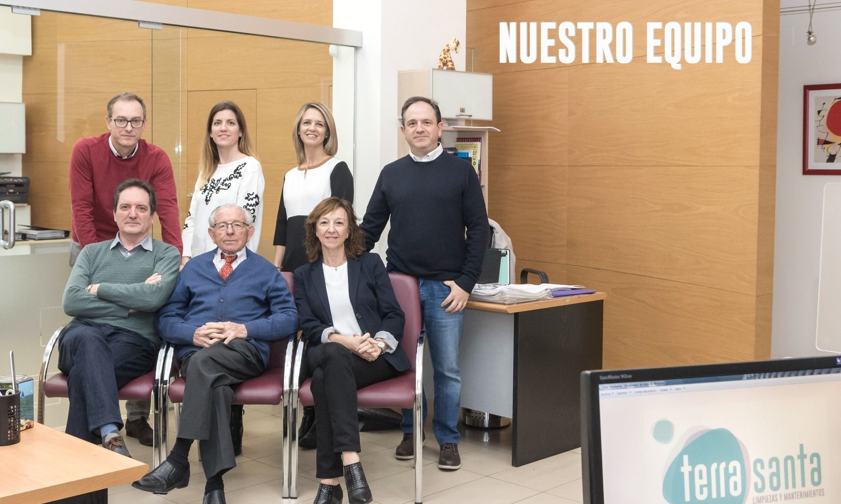 Un grupo de personas posa para una foto frente a un cartel que dice nuestro equipo.