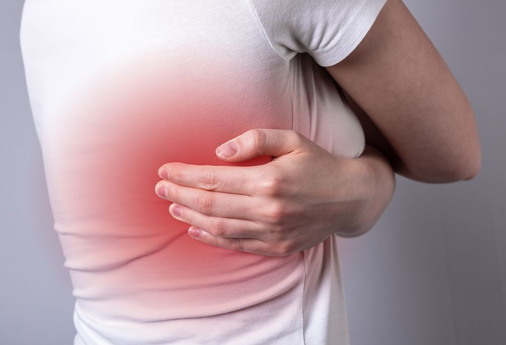 Mujer tocándose el costado, el resaltado rojo indica dolor.