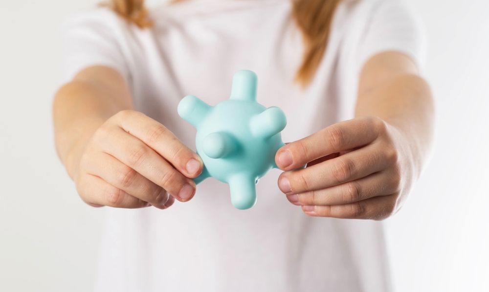 Niño sosteniendo una pelota puntiaguda de color azul claro, sobre un fondo blanco.
