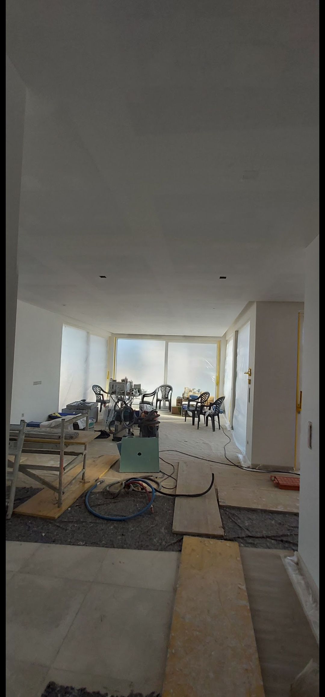 En el suelo de una habitación que se está pintando hay cubos de pintura, rodillos, pinceles y una escalera.
