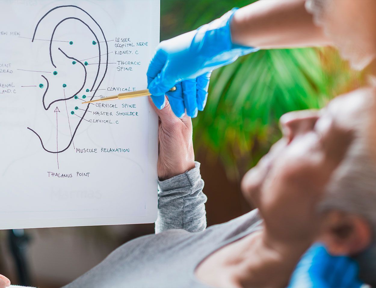 Médecin présentant les différents points ciblés sur une oreille