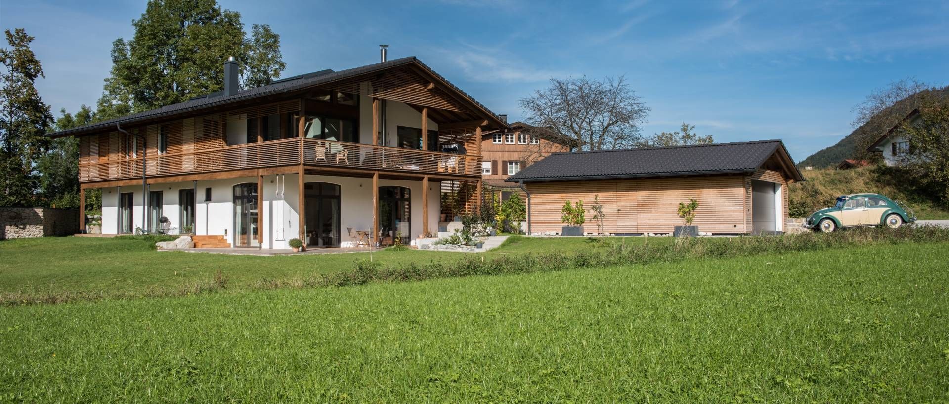 Moderne Familienhäuser aus Holz mit Wiese davor