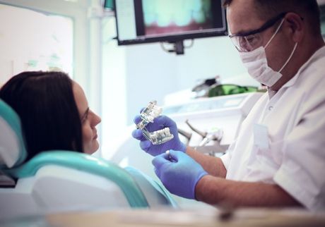 Una mujer está sentada en una silla dental mientras un dentista le examina los dientes.