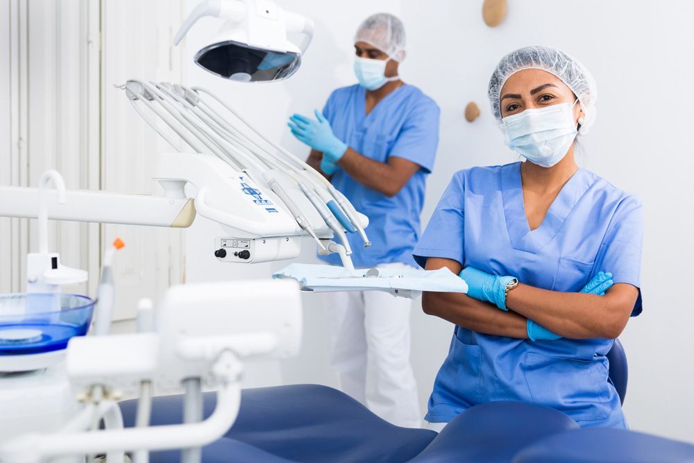 Un hombre y una mujer están de pie en un consultorio dental con los brazos cruzados.