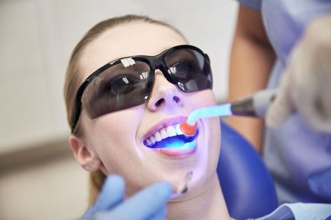 Una mujer se está blanqueando los dientes con un dentista.