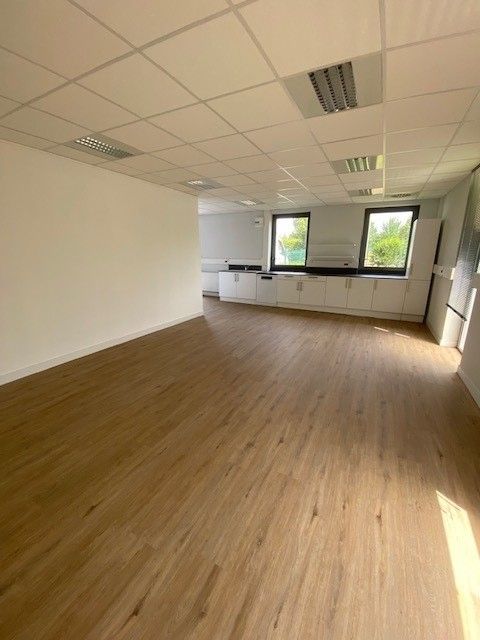 Pièce avec sol en parquet et cuisine équipée au bout de la pièce