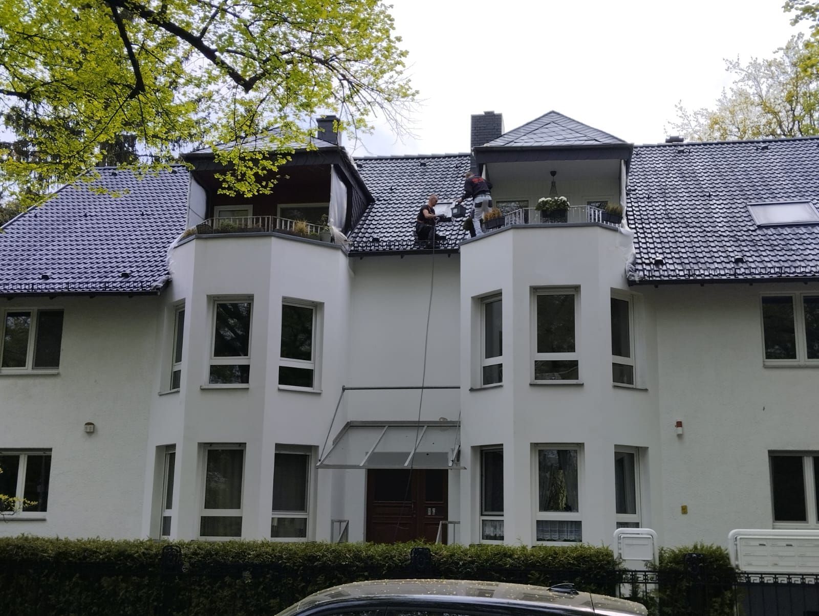 Weißes Mehrfamilienhaus mit saniertem dunklen Dach