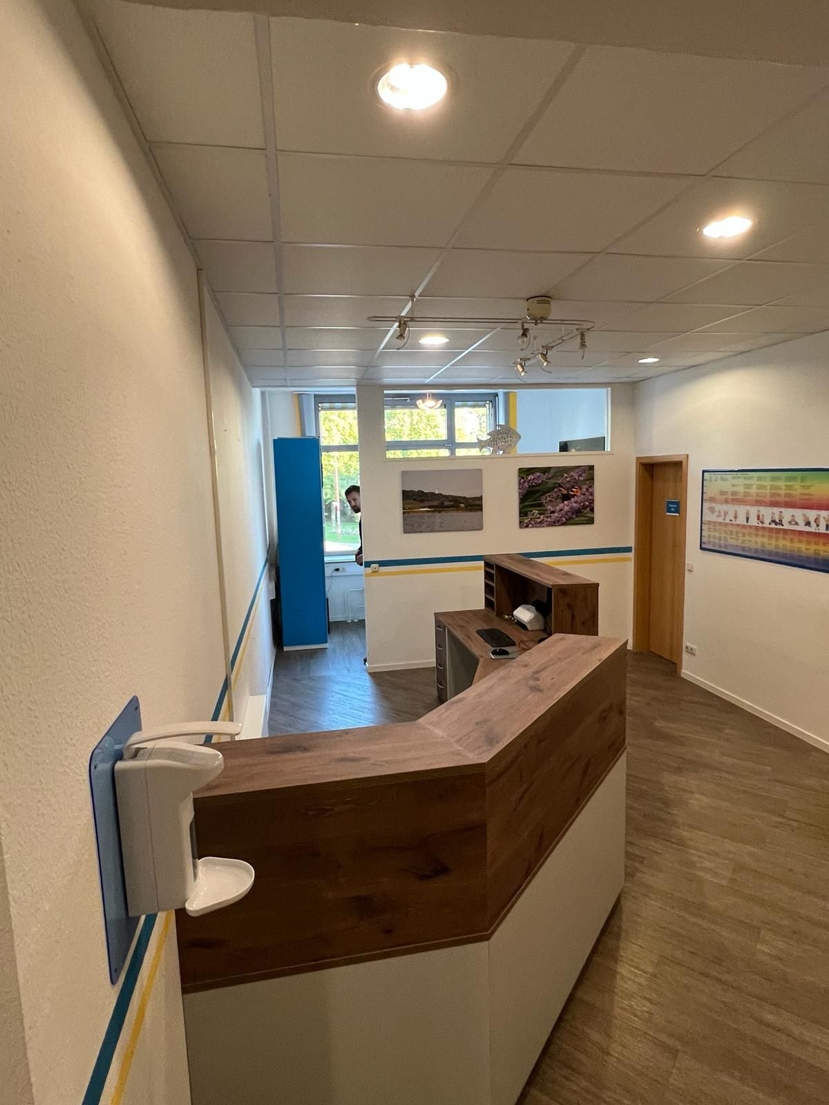 Ein großer Raum mit einem Holzschreibtisch und einem Händedesinfektionsmittel an der Wand | Tischlermeister DANIEL NETZ