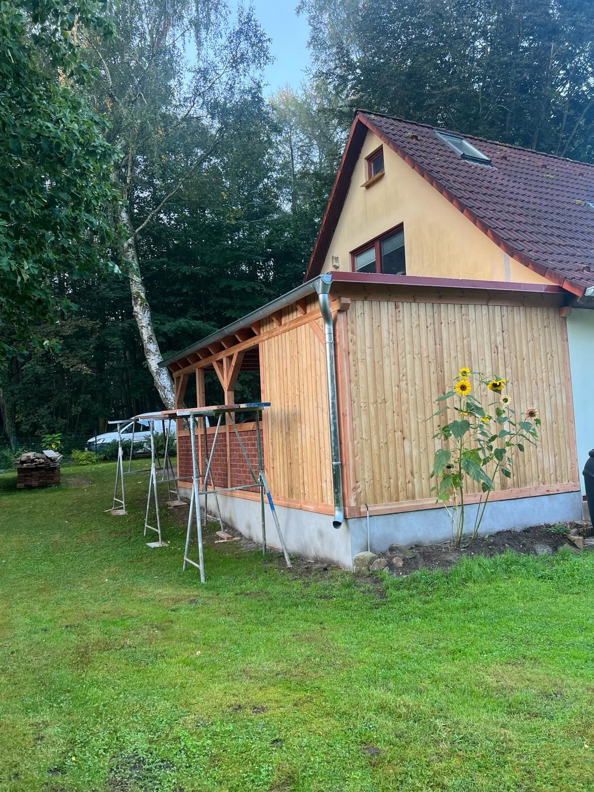 Ein Haus mit einer Holzveranda steht inmitten einer üppigen grünen Wiese.