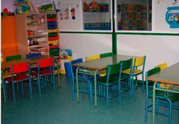 Un aula con mesas y sillas.