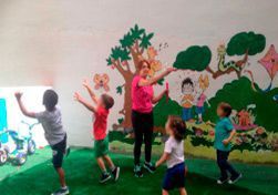 Un grupo de niños está bailando en una habitación con un mural en la pared.