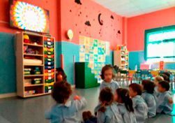 Un grupo de niños está sentado en el suelo en un aula.