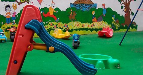 Una diapositiva está colocada sobre una alfombra verde en una habitación con un mural en la pared detrás de ella.