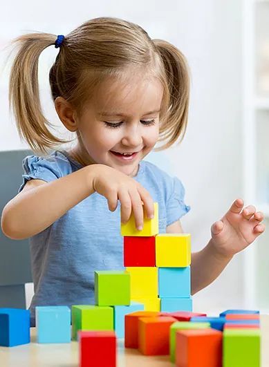 Una niña está sentada en una mesa jugando con bloques de madera.