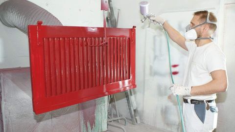 Ein Fensterladen, der gerade frisch mit roter Farbe gespritzt wird.