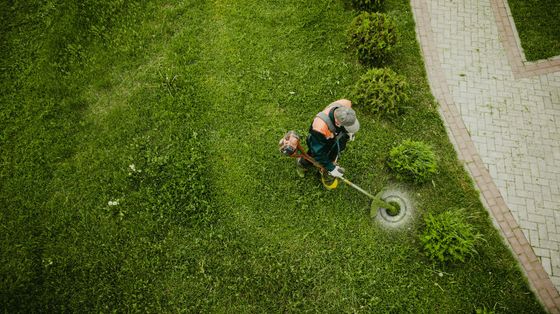 Une motobineuse rouge retourne la terre dans un jardin, projetant de la terre autour des dents.