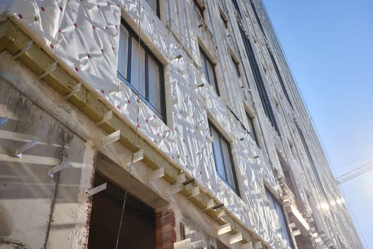 Vista exterior de un edificio en proceso de renovación, donde se aprecian los paneles aislantes fijados