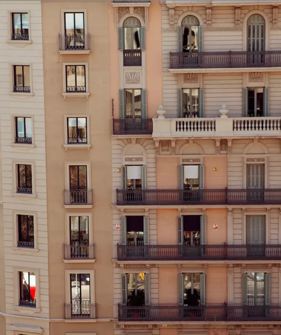 Vista de dos edificios residenciales contiguos con balcones, grandes ventanales y detalles arquitectónicos neoclásicos.