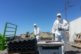 Homens vestidos com equipamento de segurança durante remoção de amianto