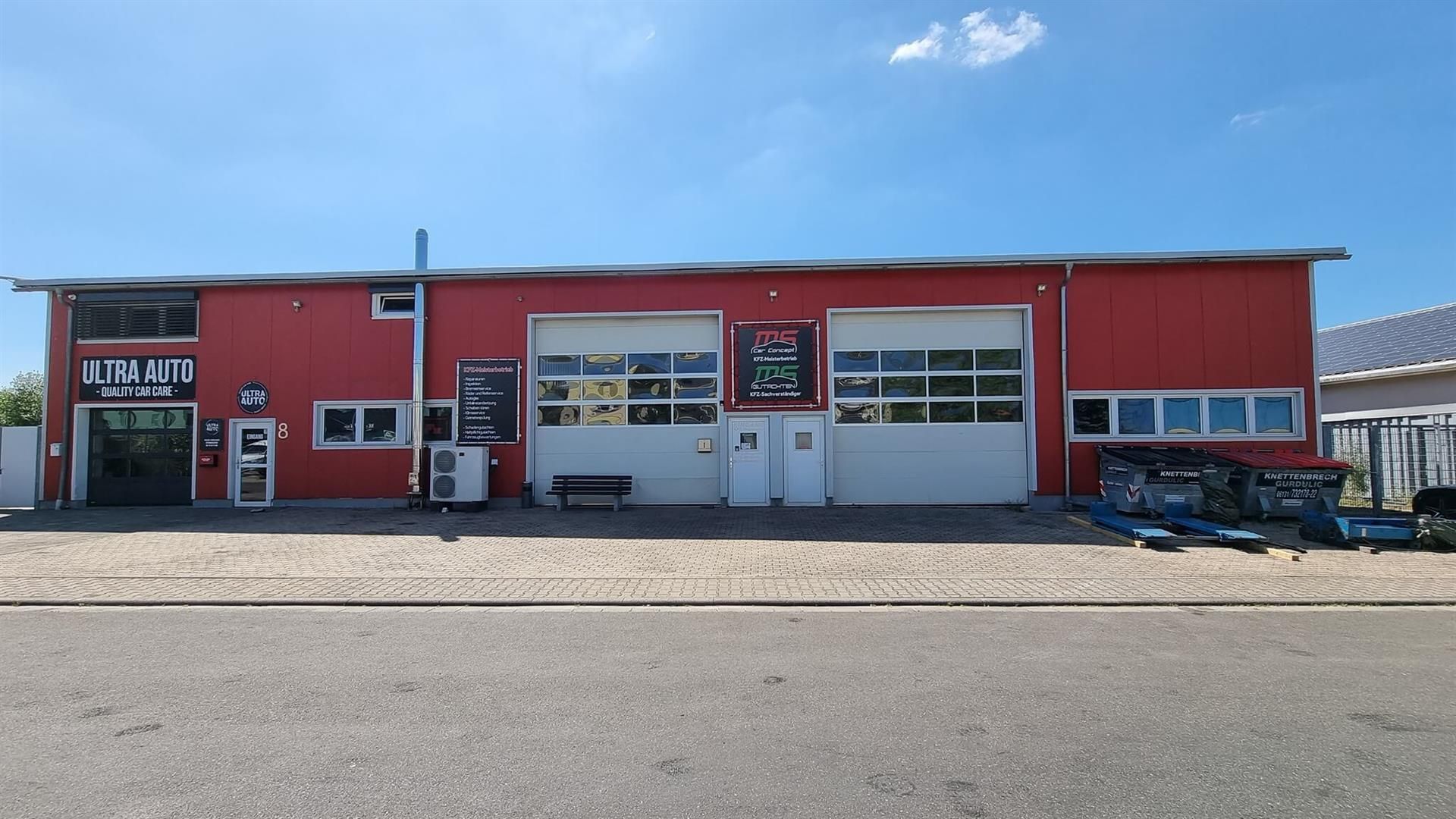 Ein rotes Gebäude mit einem weißen Garagentor und einem Schild mit der Aufschrift „rs“ darauf