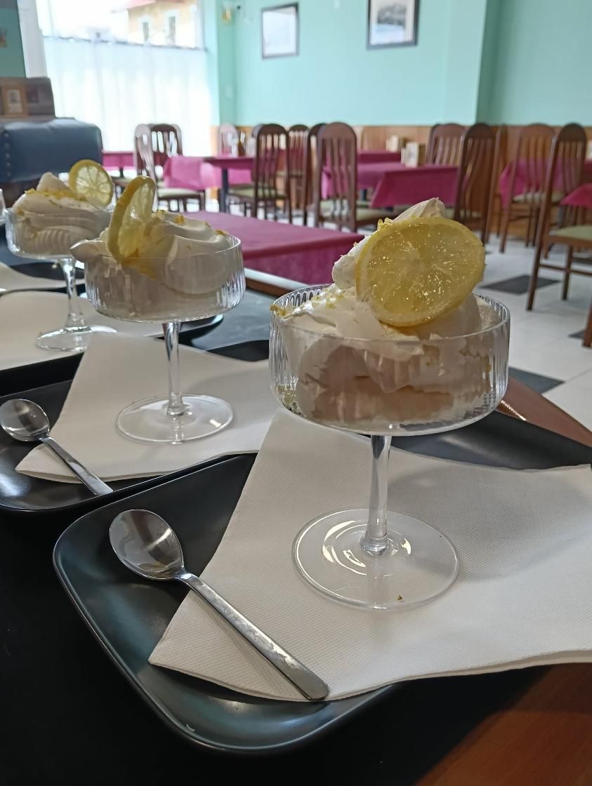 Postres de limón en platos de cristal sobre una mesa, con cucharas y un fondo de restaurante.