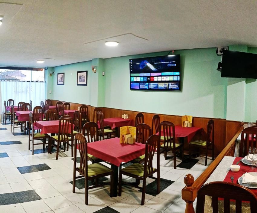 Interior del restaurante: mesas con manteles rojos, sillas de madera, paredes verdes
