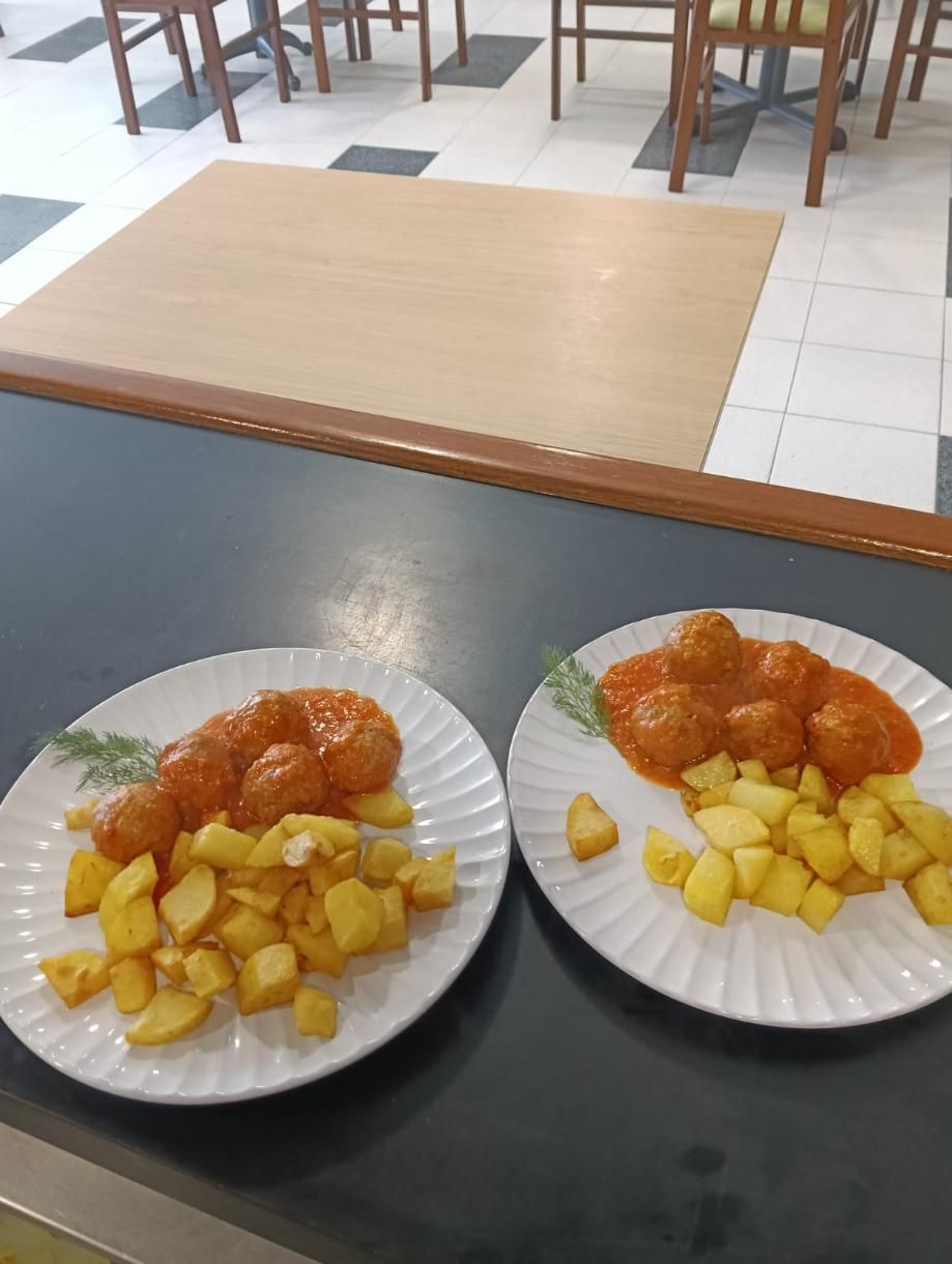 Dos platos de comida: salchicha y albóndigas con patatas en un restaurante.
