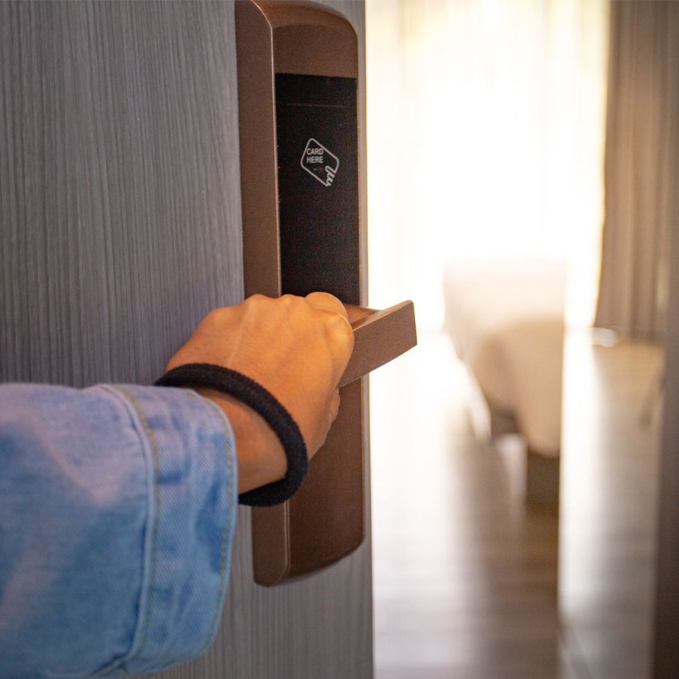 Una persona sostiene la manija de una puerta en una habitación de hotel.
