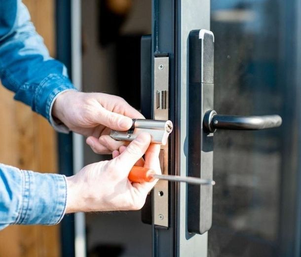 Un hombre está arreglando una cerradura de puerta con un destornillador.
