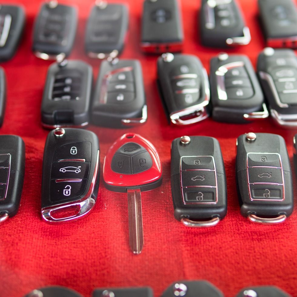 Un manojo de llaves de coche están alineadas sobre un paño rojo.