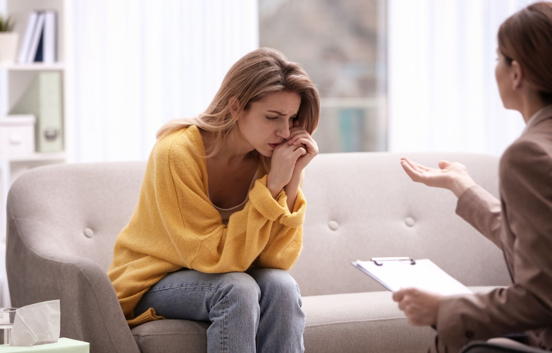 Una mujer está sentada en un sofá hablando con un terapeuta.