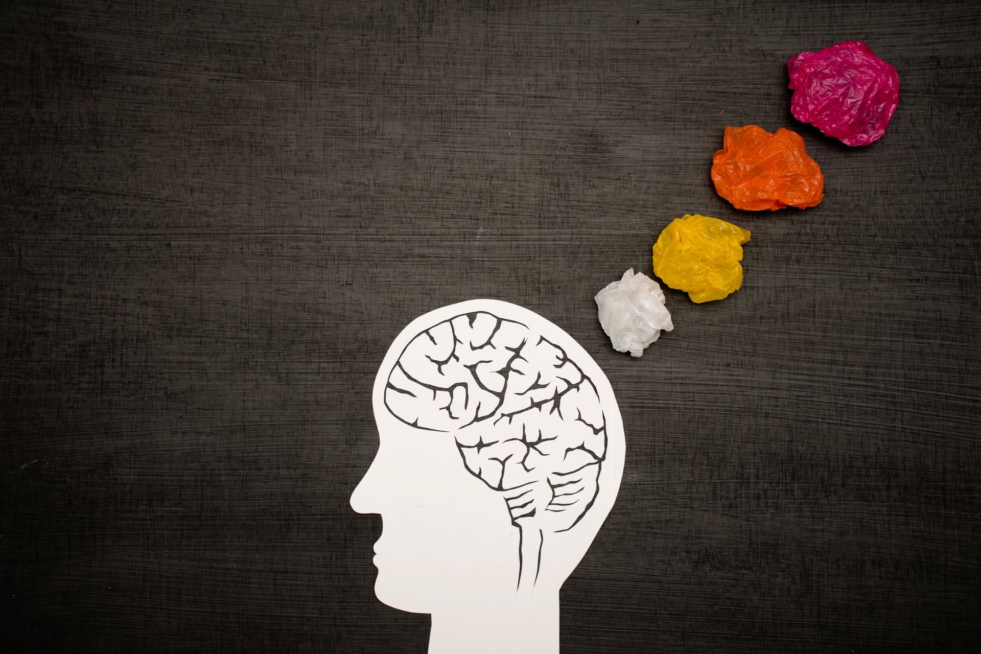 Una silueta de la cabeza de una persona con un cerebro hecho de papel arrugado.