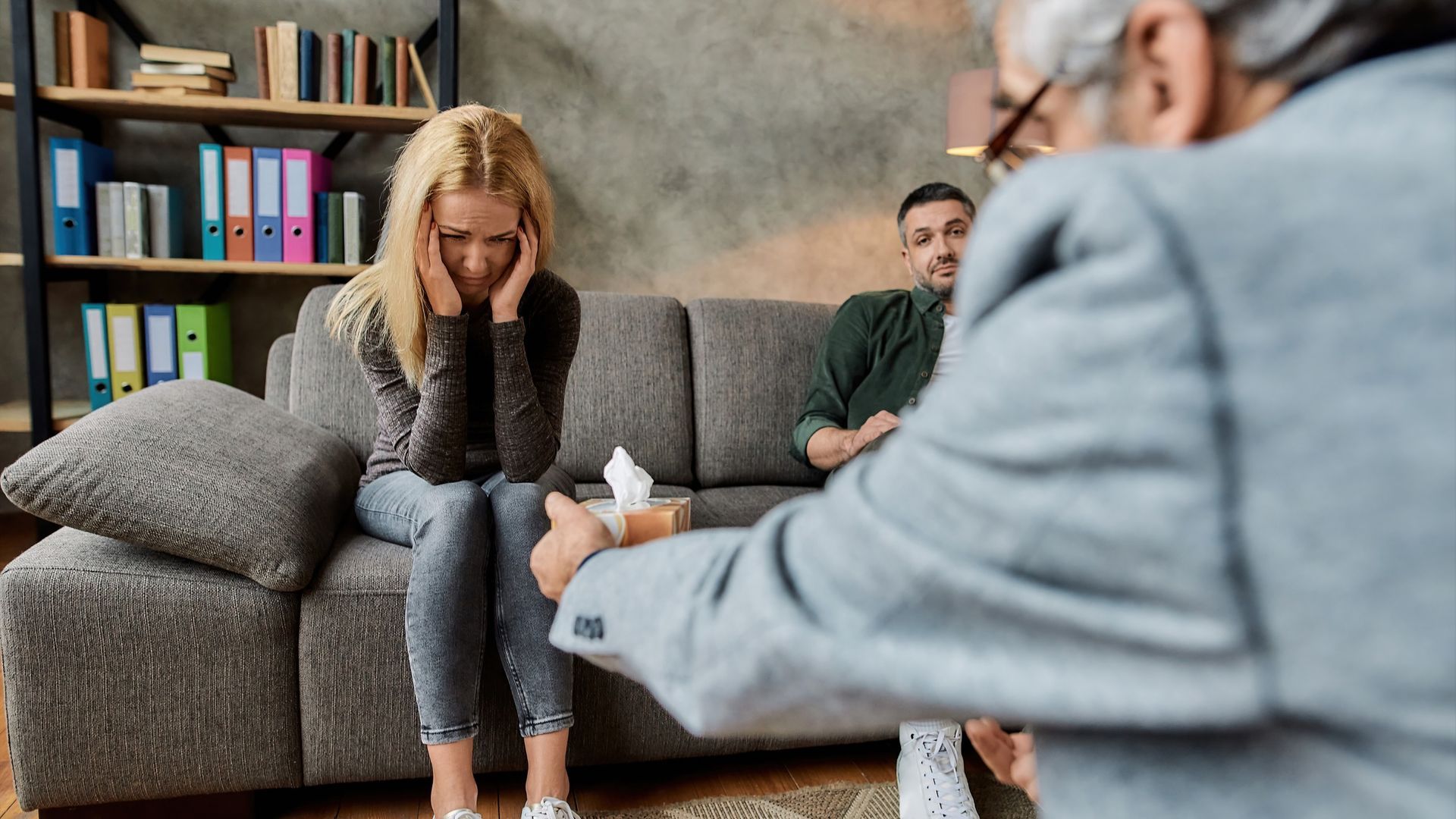 Un hombre y una mujer están sentados en un sofá hablando con un psicólogo.