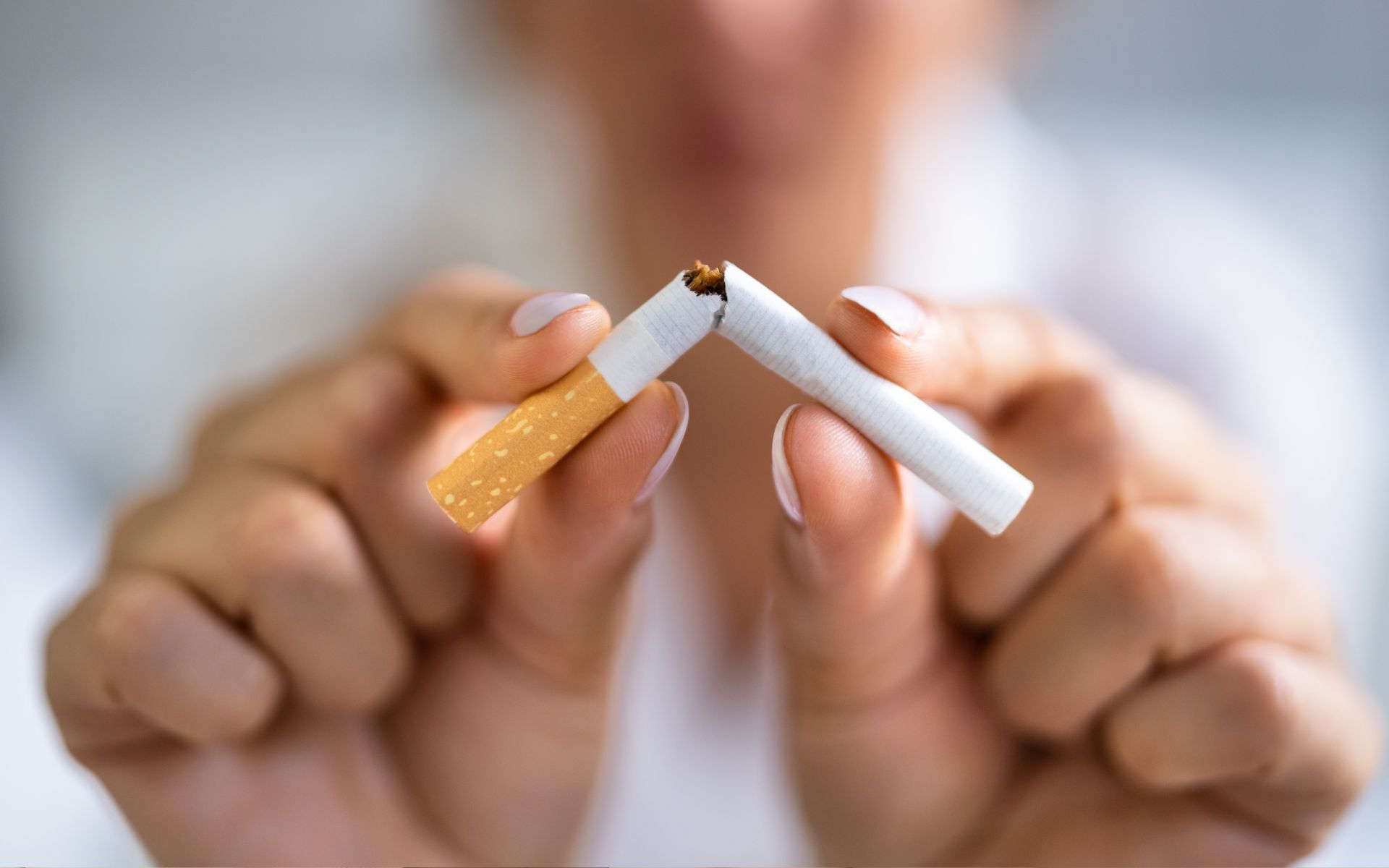 Una mujer sostiene dos cigarrillos rotos en sus manos.