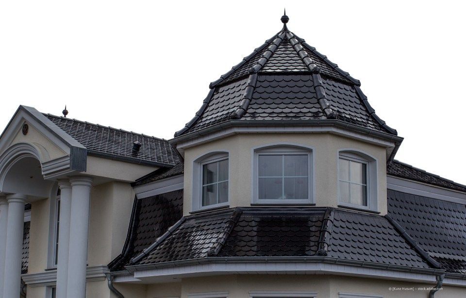 Dach eines hellen Gebäudes mit einem dunklen, sechseckigen Turm mit Fenstern und einer Turmspitze.